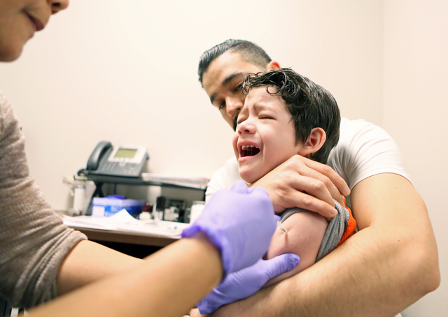 En esta foto de archivo, 8 marzo del 2016, un niño en brazos de su padre llora al ser vacunado por personal del Distrito de Salud del Sur de Nevada (SNHD) en Las Vegas. El SNHD dio a conocer que  ...