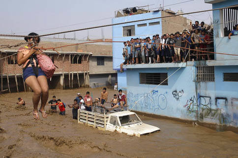 Mientras una muchedumbre atrapada observa, una mujer es rescatada con cuerdas y arnés en un lugar de Lima, Perú, el 17 de marzo del 2017 durante las lluvias torrenciales que azotaron al país. ( ...