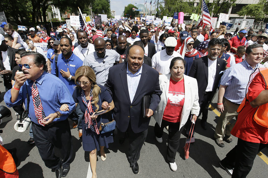 Martin Luther King III, centro, ayuda a llevar una marcha de protesta con otros activistas por el centro de Dallas, el domingo 9 de abril de 2017. Miles de personas marchan y se están reuniendo e ...