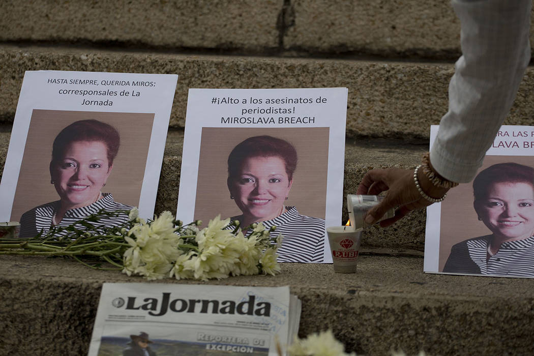 Una mujer enciende una vela junto a las fotos del periodista mexicano Miroslava Breach, abatido el jueves en el norteño estado de Chihuahua, en un altar improvisado durante una manifestación en  ...
