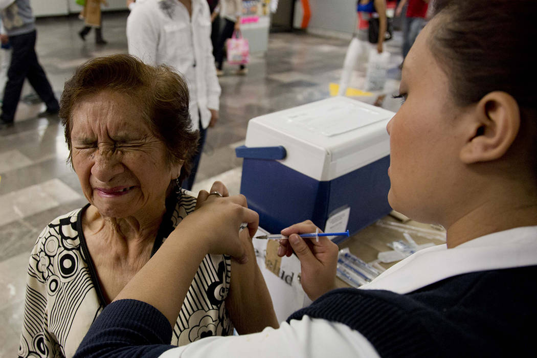 Constanza Fuentes recibe vacunación voluntaria contra la gripe por parte de la enfermera Carla Flores en una estación de metro de la ciudad de México, el lunes 27 de enero de 2014. Las autorida ...
