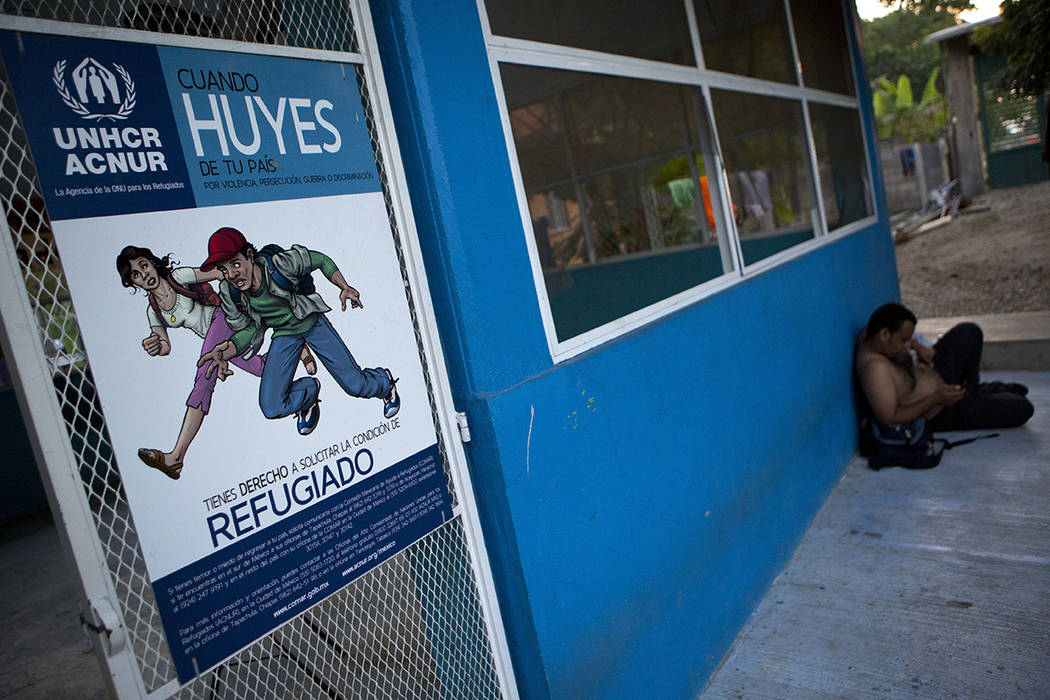 ARCHIVO- En esta foto del 6 de diciembre de 2016, un hombre descansa cerca de un cartel que informa a los migrantes que si huyen de la violencia, la persecución, la guerra o la discriminación, t ...