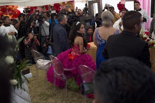 La quinceañera Rubi Ibarra, al centro, mira a su madre Anaelda mintras periodistas batallan para tomar imágenes 
durante la misa en la comunidad "La Joya", San Luis Potosi, Mexico, el lunes 26 d ...