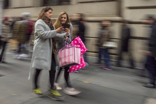 En esta foto de archivo, del 29 de noviembre del 2016, se ve a dos mujeres llevando sus bolsas con compras en la Quinta Avenida, de Nueva York. La Conference Board acaba de reportar, el 27 de dici ...