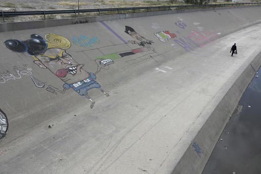 Un hombre camina el 10 de noviembre del 2016 en el lado mexicano de los límites en la frontera México - Estados Unidos, en Río Grande, Ciudad Juárez, Chihuahua, México. El graffiti es del pre ...