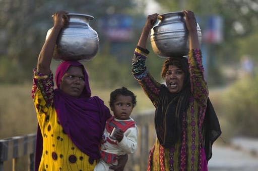 Mujeres pobres en Pakistan llevan agua en sus cabezas mientras una de ellas también carga a su bebé, el 17 de octubre del 2016, en la población de Rawalpindi, Pakistan. Ellas trabajan desde que ...