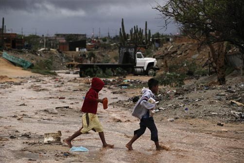 Niños de pocos recursos caminan en uno de los barrios pobres de Cabo San Lucas, Mexico, en un día de mal temporal en el 2009. (Foto Archivo/AP/Guillermo Arias).