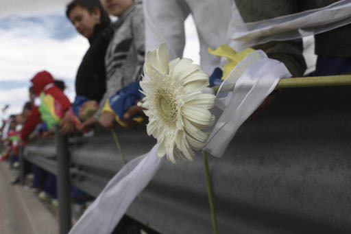 Una flor y un listón blancos se ven junto a mucha gente en un riel de contención a lo largo de Rio Grande, en el límite fronterizo de México con Estados Unidos, del lado de Ciudad Juárez, Mé ...