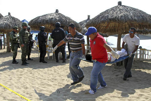 Personal forense lleva el cuerpo de un hombre baleado en la Playa Tamarindos, Acapulco, el 6 de enero del 2017. Con frecuencia el puerto de acapulco es golpeado por actos violentos lo que afecta s ...