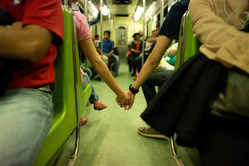 En esta foto de archivo de Sept. 18 del 2014, se ve a una pareja sostenida de las manos que no encontró lugar para ir juntos, en las horas más ocupadas del sistema de transporte "Metro", en la C ...