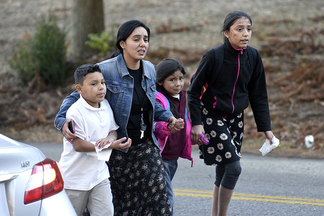 Una mujer escolta a sus tres hijos fuera del lugar del accidente donde un autobús escolar chocó y se volcó, el 21 de noviembre del 2016 en Chattanooga, Tennessee. En una conferencia de prensa l ...