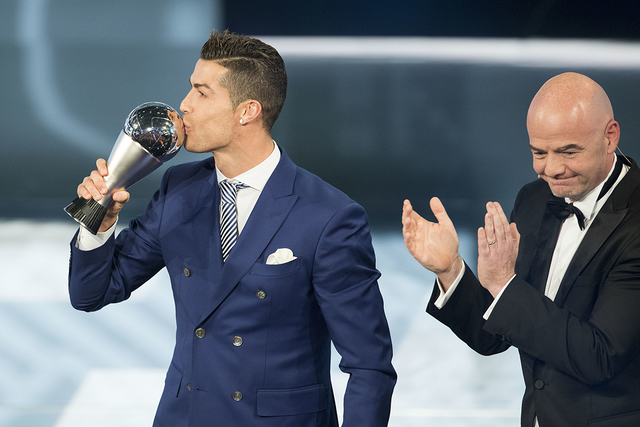 El portugués Cristiano Ronaldo, que juega en el Real Madrid, besa el trofeo, mientras que Gianni Infantino, presidente de la FIFA, aplaude después de ganar el premio a la mejor jugador masculino ...