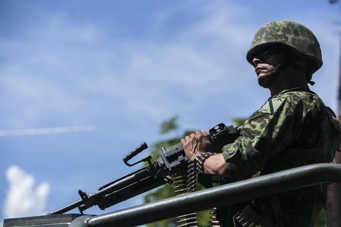 El domingo 2 de octubre del 2016 un soldado del ejército mexicano se mantiene vigilante en un vehículo militar que lleva los cuerpos de soldados muertos el día anterior en una emboscada, en la  ...