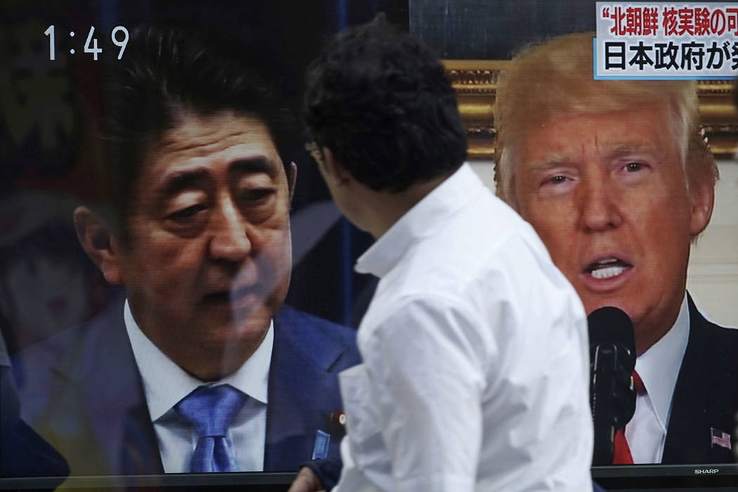 Un hombre pasa por delante de una noticia en la televisión que muestra las imágenes del primer ministro japonés, Shinzo Abe, a la izquierda, y el presidente de Estados Unidos, Donald Trump, a l ...