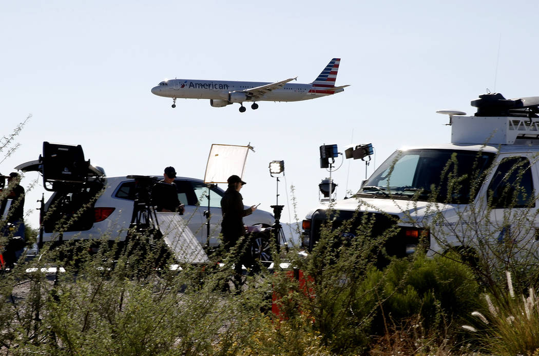 Un avión de American Airways vuela por encima de camiones televisión por satélite cerca del Aeropuerto Internacional McCarran el lunes 2 de octubre de 2017 en Las Vegas. Bizuayehu Tesfaye Las V ...