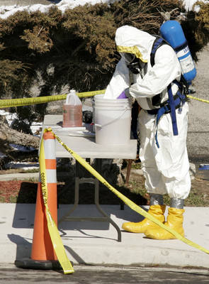 Una persona vestida con un atuendo HAZMAT para sustancias peligrosas trabaja fuera de una casa el domingo 2 de marzo de 2008 en Riverton, Utah. Los agentes del FBI registraron la casa y dos unidad ...