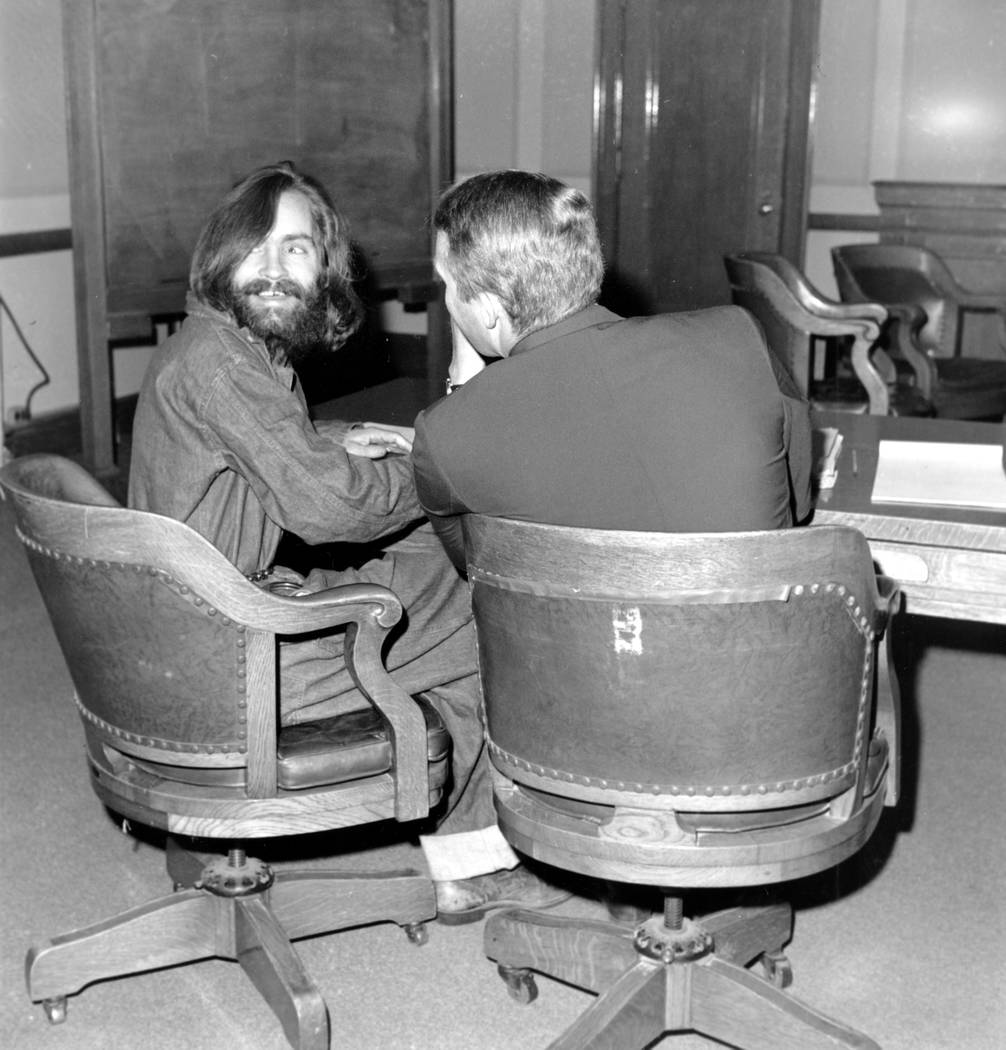 El líder de culto Charles Manson mira hacia atrás y sonríe mientras su abogado, el defensor público Fred Schaefer, habla con él en Independence, California, el 4 de diciembre de 1969. Manson  ...