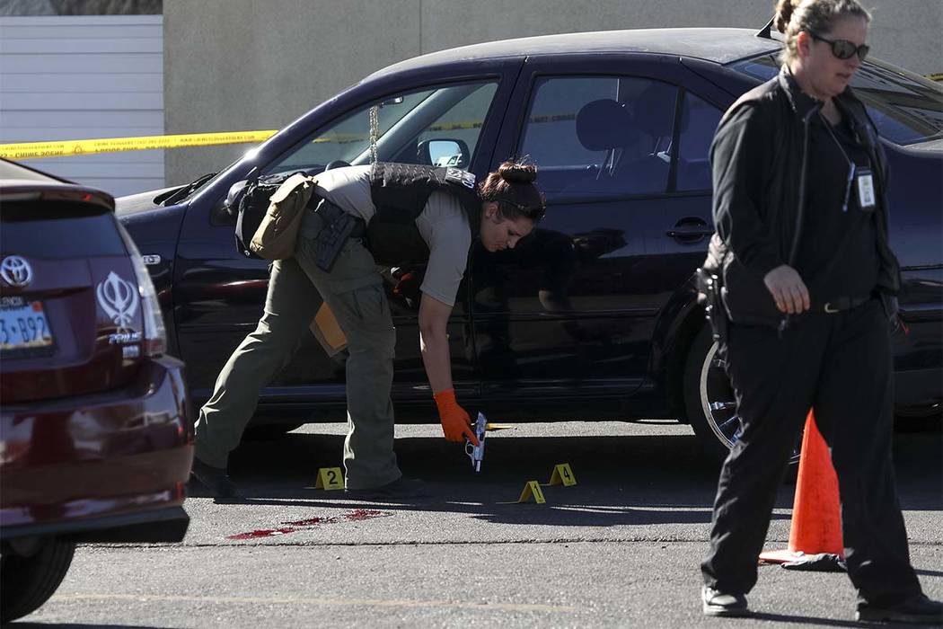 Los investigadores de la escena del crimen recogen un arma como evidencia en la escena de un tiroteo ocurrido en un callejón detrás de una tienda 7-Eleven cerca de la intersección de East Sunse ...
