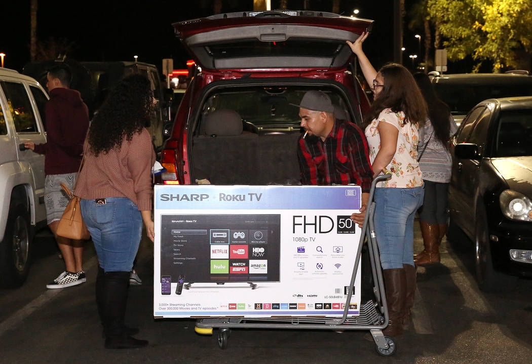 Daniel López, al centro, carga su televisor de pantalla plana en el maletero de una SUV a las 12:44 a.m. después de las compras de Black Friday en Best Buy en Henderson el 24 de noviembre de 201 ...