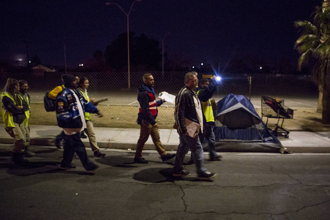 Voluntarios para el censo anual sin hogar del Condado de Clark caminan frente a un campamento en Veterans Memorial Drive en Las Vegas durante el censo anual de personas indigentes del Condado de C ...