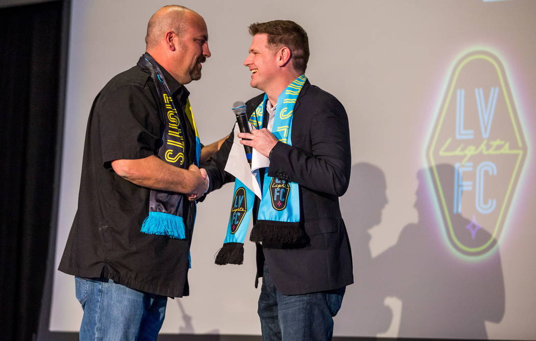 El propietario del equipo de fútbol de Las Vegas Lights FC, Brett Lashbrook, da la mano a Loren Becker, Gerente de Zappos Experience y Community Team, durante el evento de revelación de camiseta ...