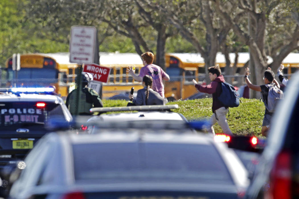 Los estudiantes corren con las manos en el aire después de un tiroteo en Marjory Stoneman Douglas High School en Parkland, Fla., El miércoles, 14 de febrero de 2018. (John McCall / South Florida ...