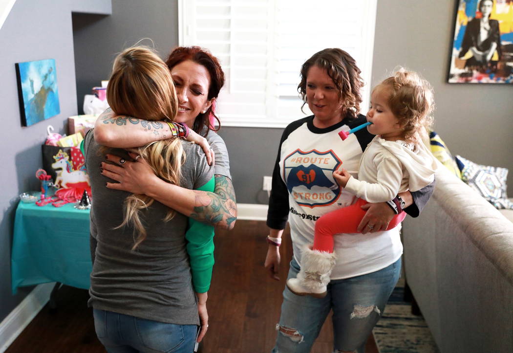 La sobreviviente de Route 91 Mindy Foster abraza a Colie Knoke, otra sobreviviente, mientras Jennifer Holub lleva a Aubri, la hija de Knoke de 2 años, después de recibir un cheque de la Route91  ...