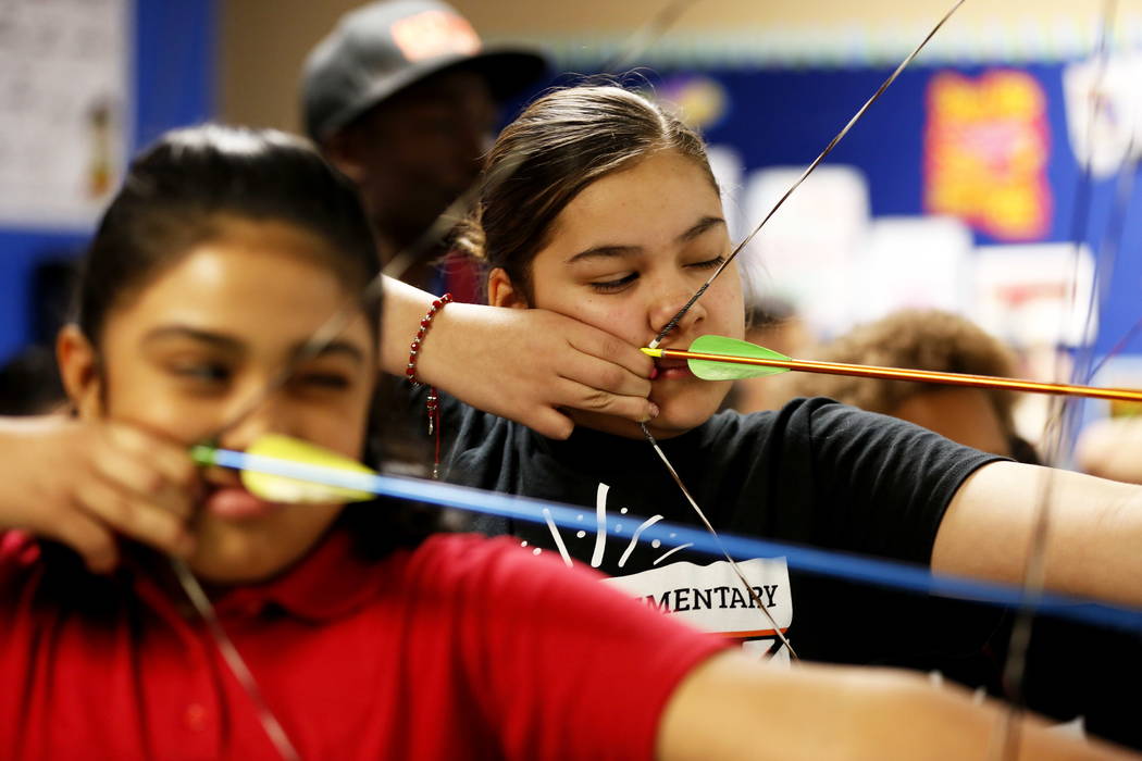 Maryani Matos, de 11 años, izquierda, y Maureen Ruiz, de 12, practican con el resto del equipo de tiro con arco después de clases en la escuela Primaria Squires en el Norte de Las Vegas el jueve ...