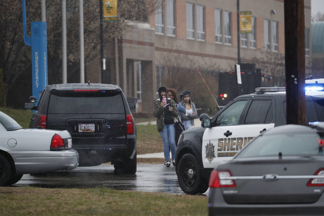 Dos estudiantes y una madre abandonan Great Mills High School, en el escenario del tiroteo, el martes 20 de marzo de 2018 en Great Mills, Maryland. El tiroteo dejó al menos tres personas heridas, ...