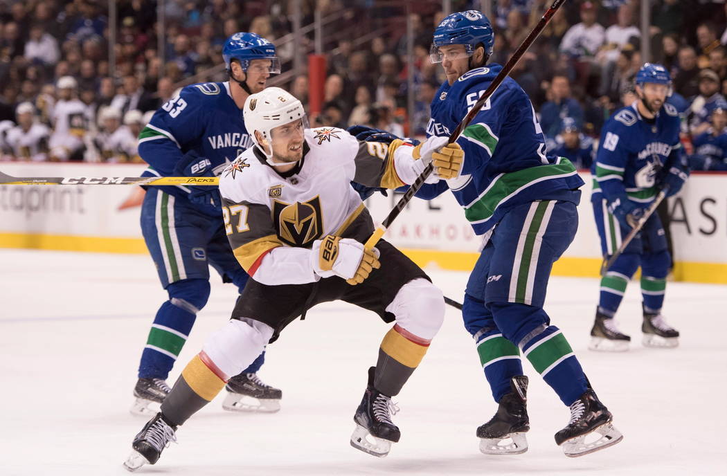 El defensor de Vegas Golden Knights Shea Theodore (27) pelea por el control del disco con el defensor de Vancouver Canucks Alex Biega durante el primer periodo de un juego de hockey de la NHL el m ...