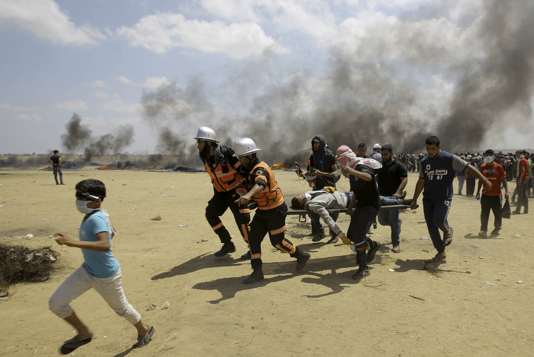 Médicos y manifestantes palestinos evacuan a un joven herido durante una protesta en la frontera de Gaza con Israel, al este de Khan Younis, Gaza, el lunes 14 de mayo de 2018. Miles de palestinos ...