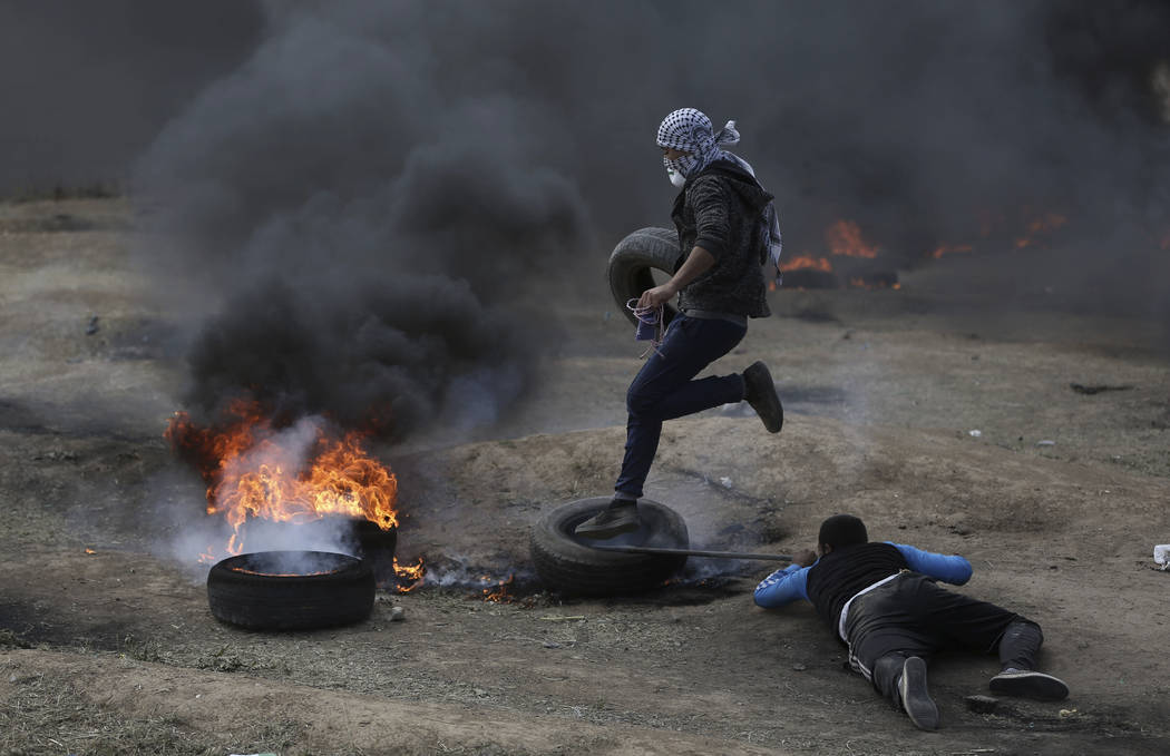 Los manifestantes palestinos queman neumáticos durante una protesta en la frontera de Gaza con Israel, el lunes 14 de mayo de 2018. Miles de palestinos protestan cerca de la frontera de Gaza con ...