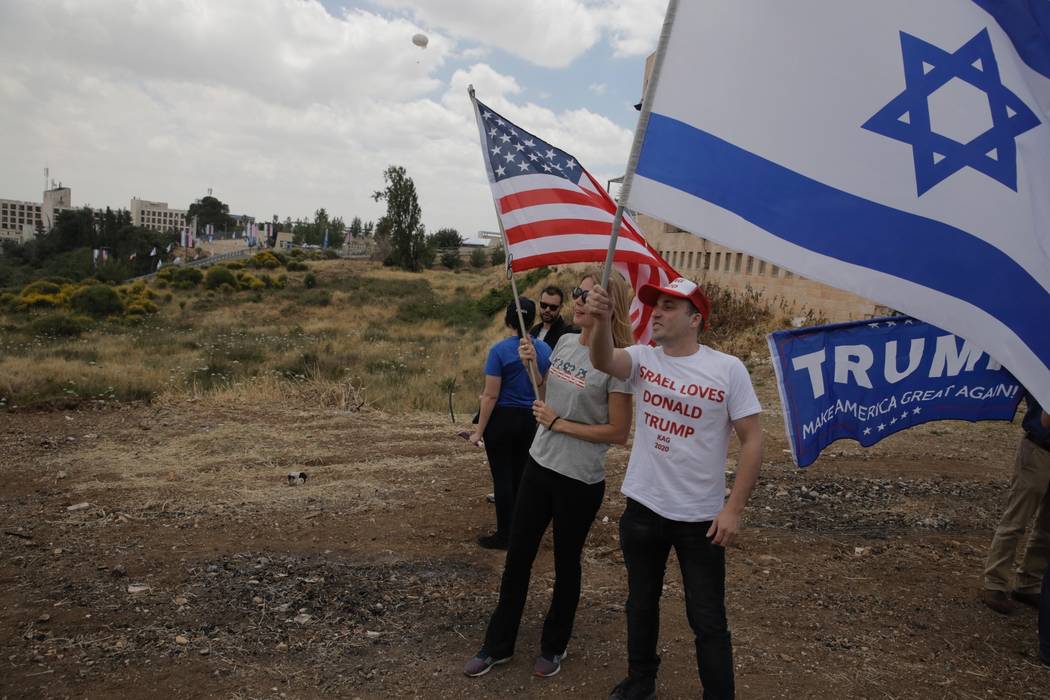 Los israelíes sostienen banderas estadounidenses e israelíes con la nueva embajada de EE.UU. En el fondo en Jerusalén, el lunes 14 de mayo de 2018. Israel se preparó para la inauguración fest ...