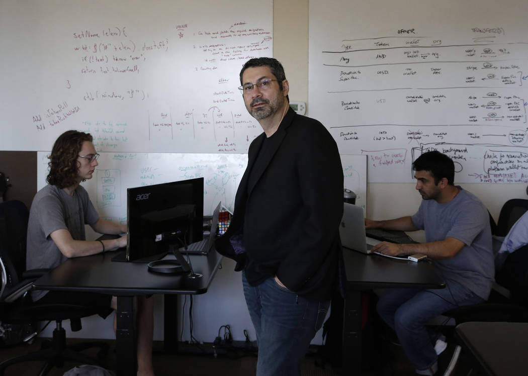 Rick Duggan, CEO de Concierge Software Design, posa para la foto como Triston Jones, izquierda, y Kandarp Dave, ambos ingenieros senior de software, trabajan en su proyecto en su oficina de Las Ve ...