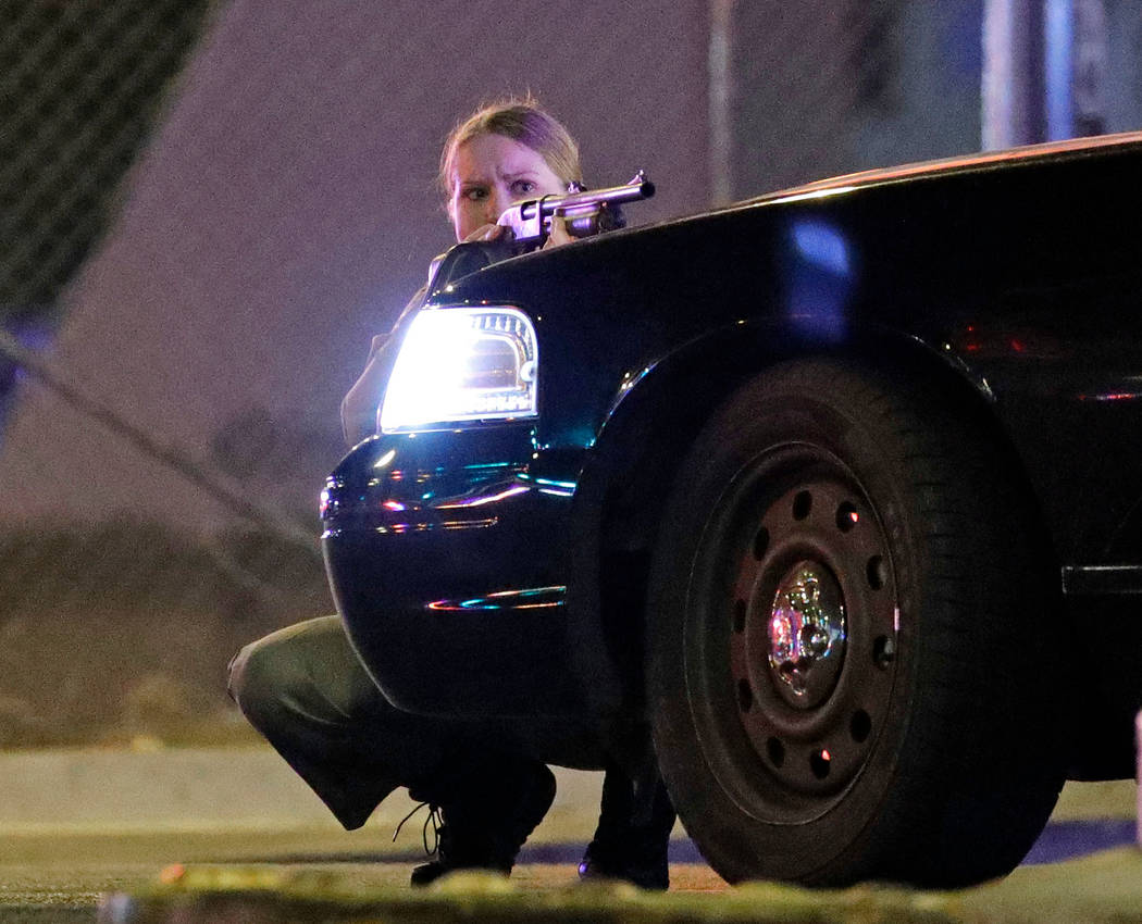 Un agente de policía se cubre detrás de un vehículo policial durante el tiroteo masivo cerca de Mandalay Bay en Las Vegas Strip el 1 de octubre de 2017. (John Locher / AP)
