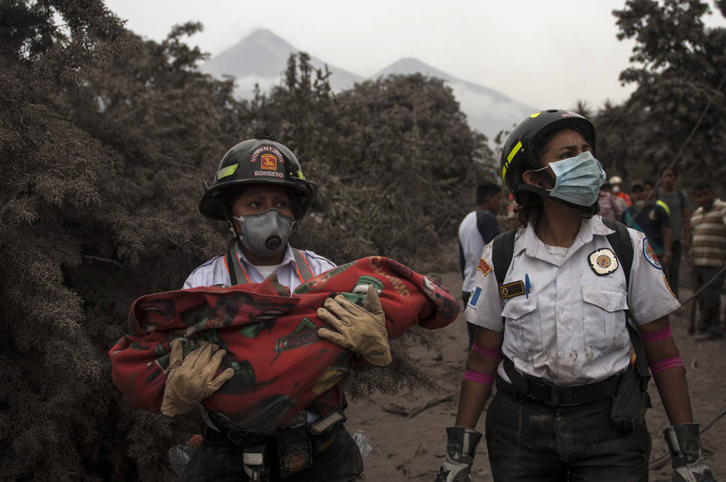Un bombero lleva el cuerpo de un niño recuperado cerca del Volcán de Fuego, en Escuintla, Guatemala, el lunes 4 de junio de 2018. Una ardiente erupción volcánica en el centro-sur de Guatemala ...