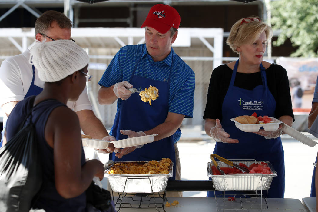El candidato a la Corte Suprema, Brett Kavanaugh, en el centro, sirve macarrones con queso a las personas sin hogar mientras trabaja como voluntario en Catholic Charities, el miércoles 11 de juli ...