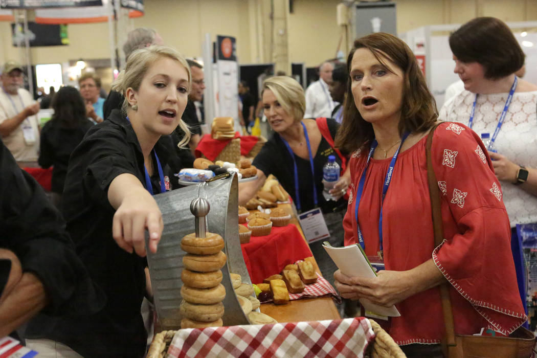 Christine Collins de la Bake Crafters Food Company, señala productos a Lory Hayon, dietista registrada del Distrito Escolar del Condado de Clark, durante la conferencia anual de la Asociación de ...