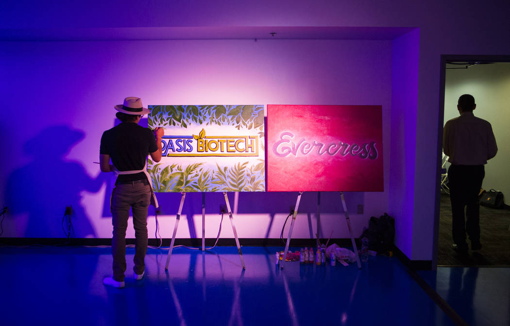 Jeremiah Kaniaupio, izquierda, pinta el logotipo de Oasis Biotech durante un gran evento de inauguración de la empresa agrícola de interior en Las Vegas el miércoles 18 de julio de 2018. Chase ...