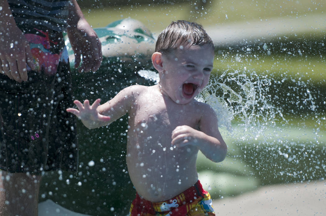 Matthew Perkins, de un año, juega en el salpicadero con su padre Nick en el Centennial Hills Park en Las Vegas el jueves, 27 de junio de 2013. Excesivas advertencias de calor están en su lugar d ...