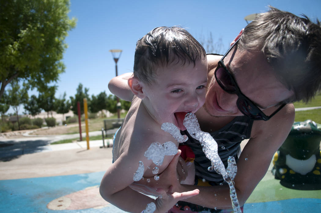 Nick Perkins y su hijo Matthew, de un año, se refrescan en el parque acuático en el Centennial Hills Park en Las Vegas el jueves 27 de junio de 2013. Las advertencias de calor excesivo están vi ...