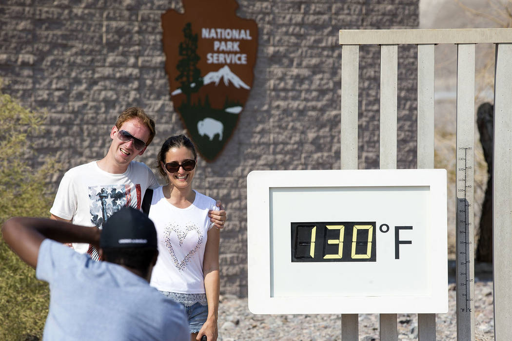 Una pareja posa en el termómetro Furnace Creek Visitor Center en el Parque Nacional Death Valley, California, el jueves 26 de julio de 2018. La temperatura oficial en el parque aumentó a 127 el ...