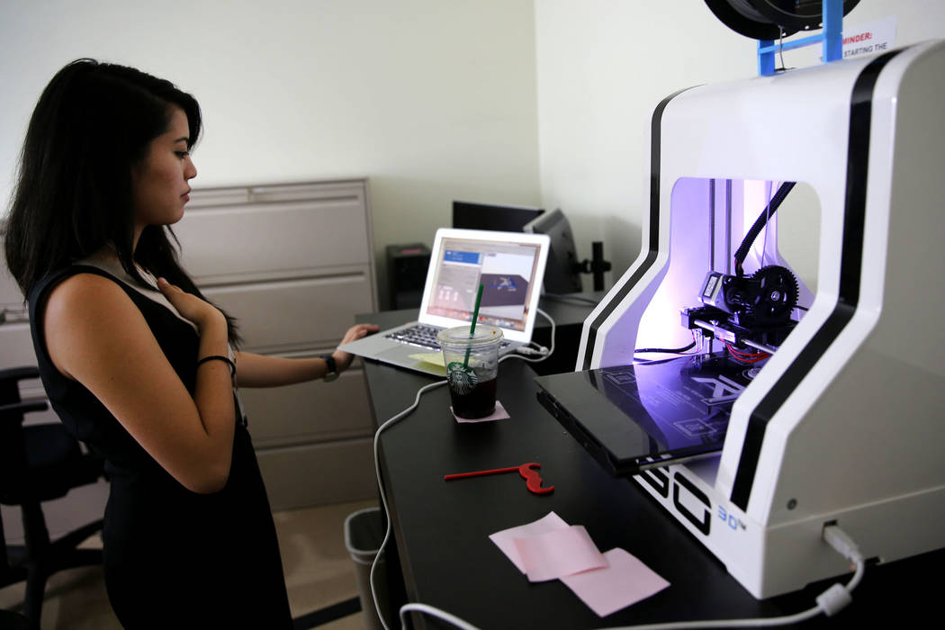 Talitha La Putt, y pasante del Centro de Desarrollo de Pequeñas Empresas, demuestra una impresora 3D durante la jornada de puertas abiertas para Nevada Business Development Services ubicada en la ...