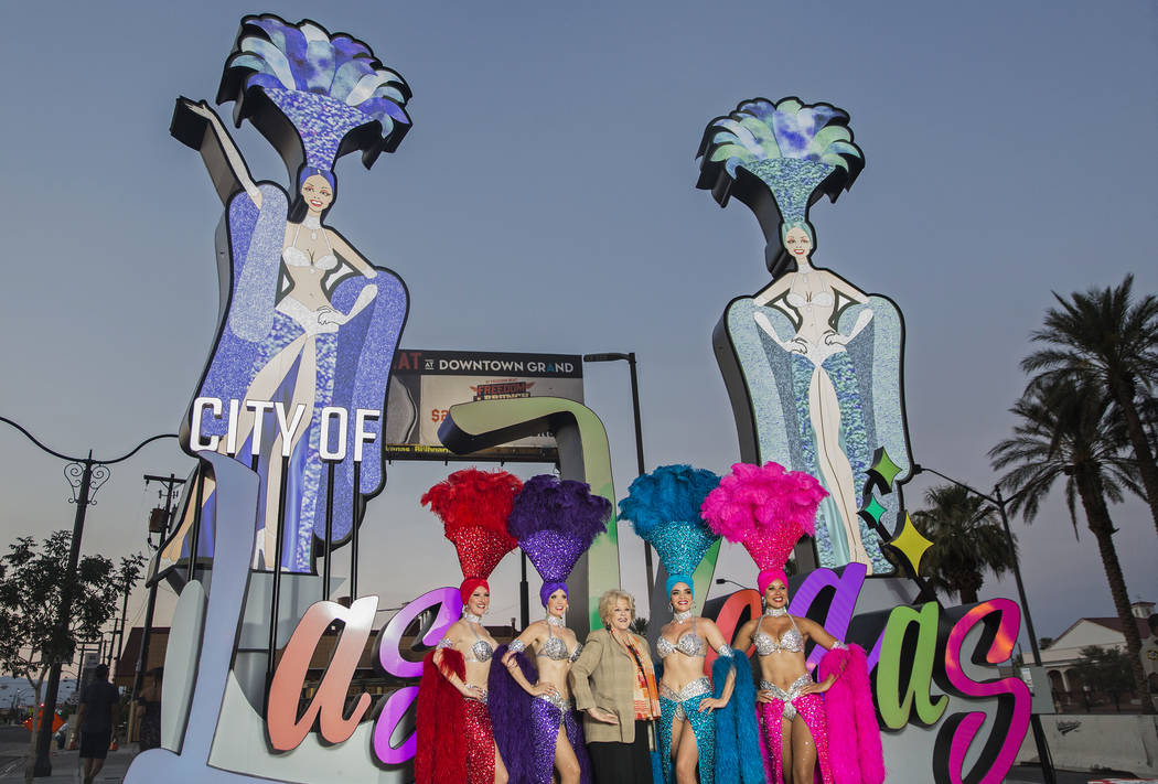 La alcaldesa de Las Vegas, Carolyn Goodman, tercera desde la izquierda, se toma fotos con un grupo de showgirls durante una ceremonia de inauguración para la nueva puerta de entrada de la ciudad ...