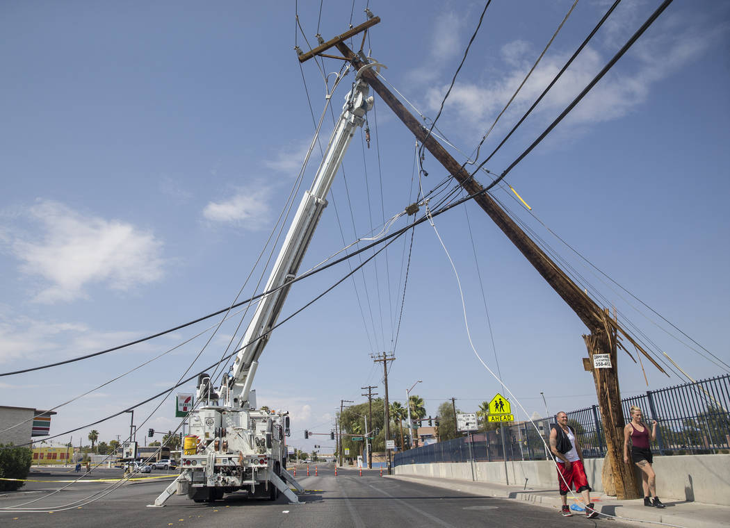 Los residentes de Las Vegas pasan cerca de los equipos de NV Energy que trabajan para restaurar la energía en el área de Fremont Street y Bruce Street el domingo, 12 de agosto de 2018, en Las Ve ...