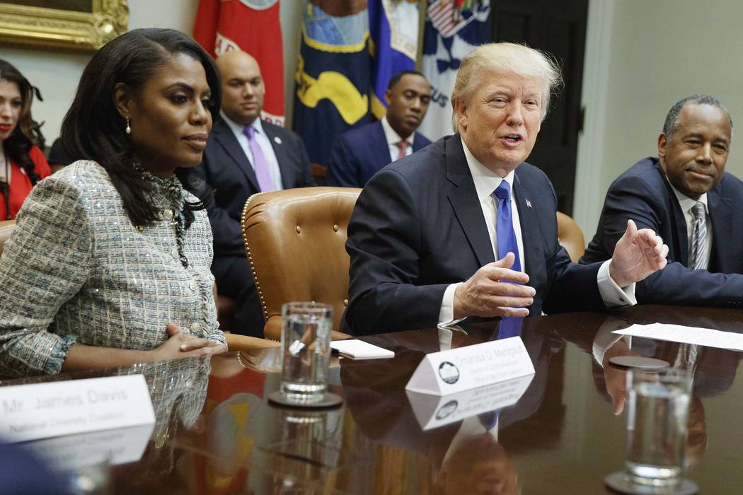 El presidente Donald Trump, en el centro, está flanqueado por el miembro de la Casa Blanca Omarosa Manigault Newman, izquierda, y el entonces designado secretario de Vivienda y Desarrollo Urbano, ...