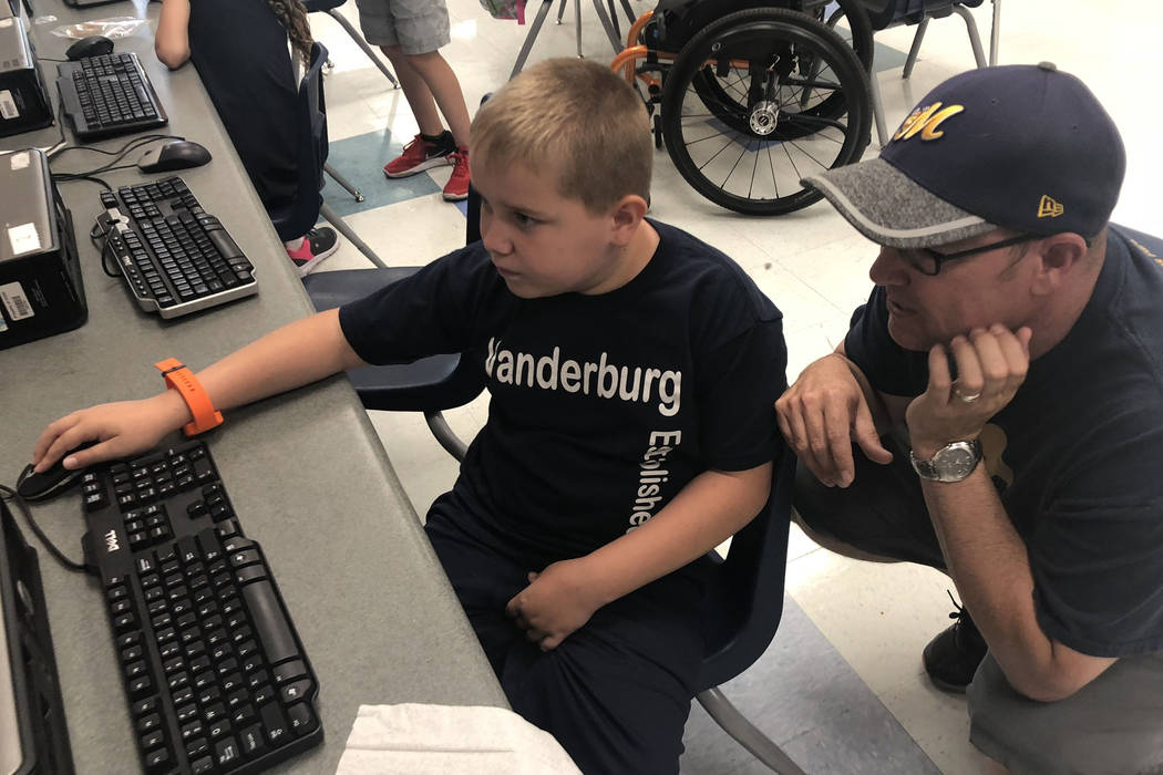 Dylan Chalmers, de siete años, estudiante de segundo grado con parálisis cerebral, trabaja en una computadora después de la escuela en la Primaria Vanderburg con su padre, Scott, el 24 de agost ...