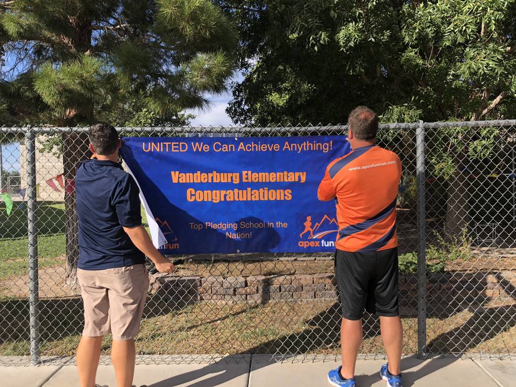 Frank Endellicate y Rob Wiatt, empleados de Apex Fun Run, cuelgan un cartel en la Escuela Primaria Vanderburg en Henderson el 24 de agosto, celebrando el logro de la escuela. Dylan Chalmers, de si ...