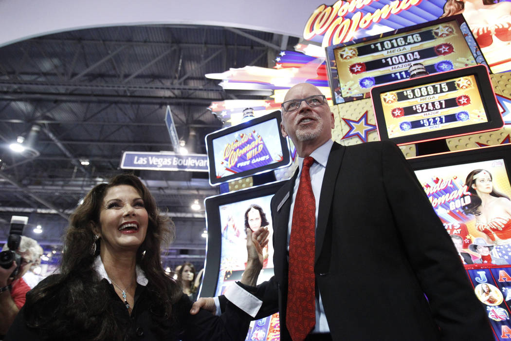 Lynda Carter, izquierda, estrella de la serie de televisión "Wonder Woman", y Richard Haddrill, CEO de Bally Technologies, posan para las fotos en la presentación de la máquina tragamonedas Bal ...