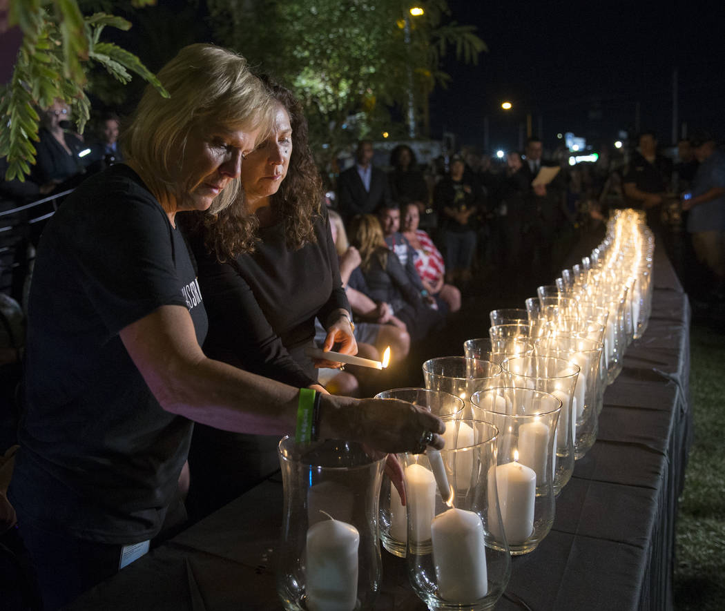 Esther Reincker, izquierda, y Mauricia Baca encienden velas para las 58 víctimas del tiroteo del 1 de octubre a las 10:05 pm, hora exacta en que comenzó el tiroteo el año pasado, durante una ce ...